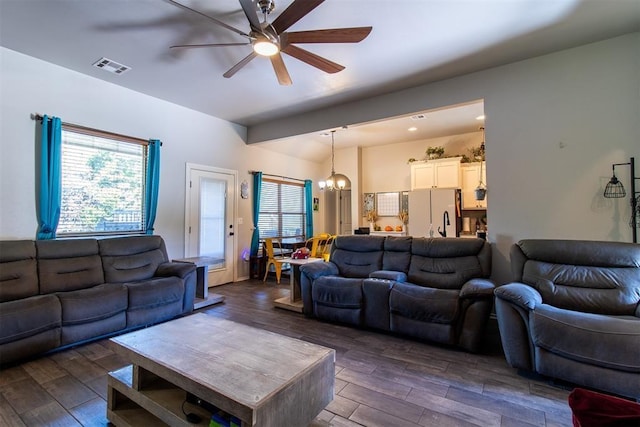 living room with visible vents, dark wood-style flooring, and ceiling fan with notable chandelier