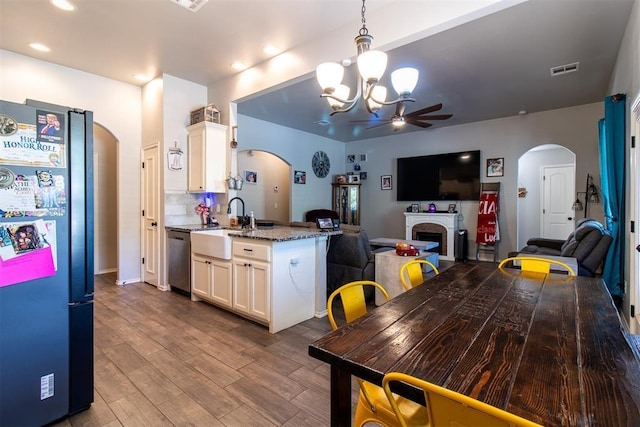 kitchen with arched walkways, a fireplace, visible vents, stainless steel dishwasher, and freestanding refrigerator