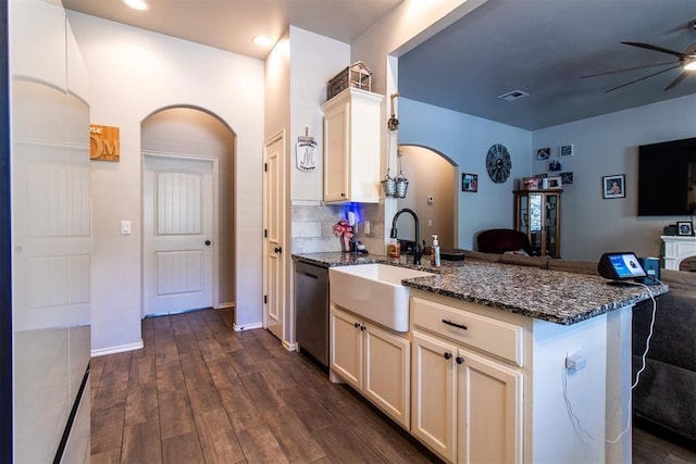 kitchen featuring arched walkways, a sink, a ceiling fan, open floor plan, and stainless steel dishwasher