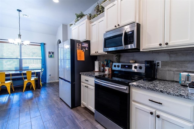 kitchen with dark wood finished floors, stainless steel appliances, tasteful backsplash, white cabinets, and dark stone counters