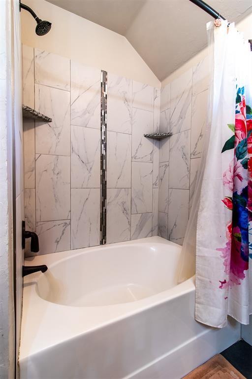 full bath featuring shower / bath combo and vaulted ceiling