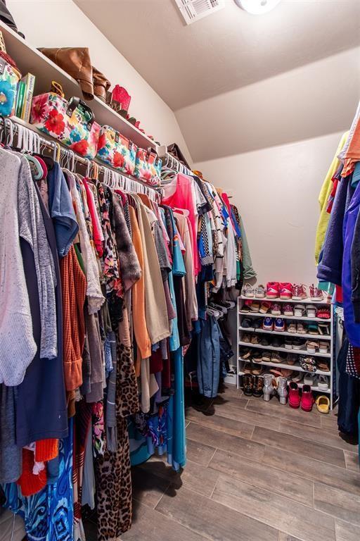 spacious closet with wood tiled floor, visible vents, and vaulted ceiling