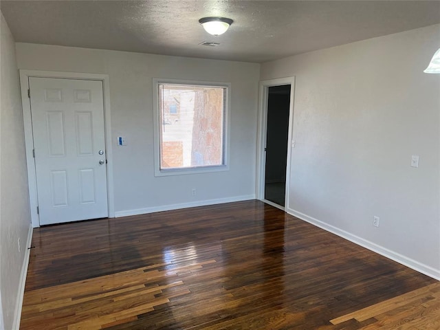 unfurnished room featuring dark wood-style flooring, a textured ceiling, and baseboards