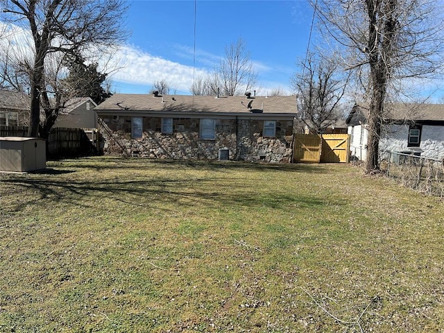 back of house featuring a gate, fence, and a lawn