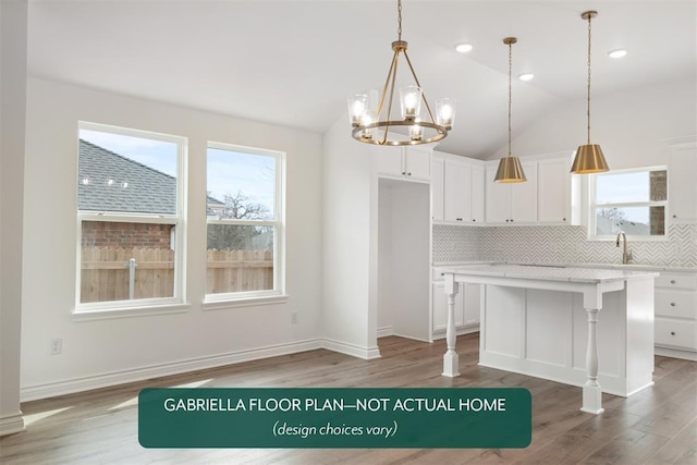 kitchen with lofted ceiling, plenty of natural light, and white cabinetry