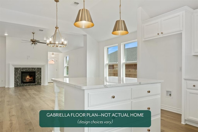 kitchen featuring lofted ceiling, visible vents, a high end fireplace, a kitchen island, and light wood-type flooring