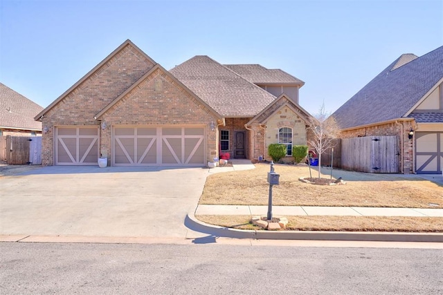 view of front of property with brick siding, driveway, an attached garage, and fence