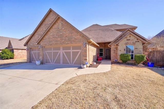 view of front facade featuring a shingled roof, concrete driveway, stone siding, an attached garage, and brick siding