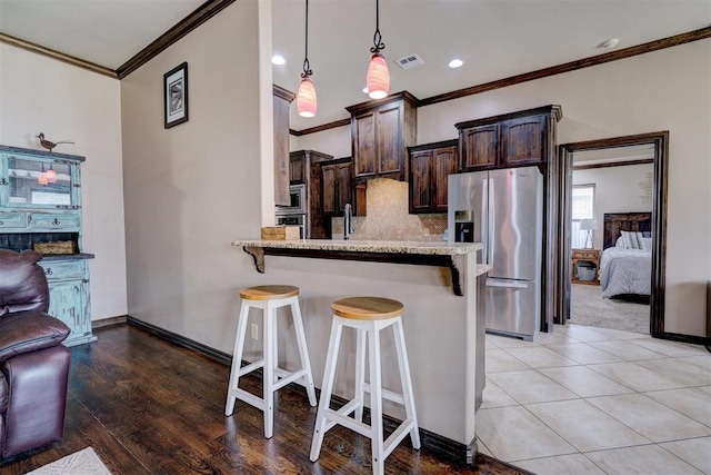 kitchen featuring appliances with stainless steel finishes, a breakfast bar, dark brown cabinets, and light stone countertops