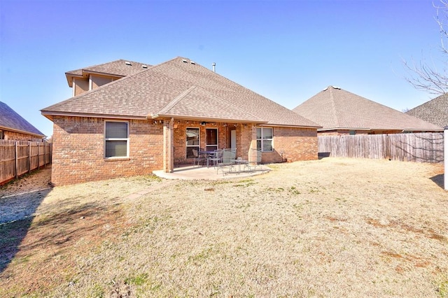 back of property featuring a patio area, a fenced backyard, roof with shingles, and brick siding