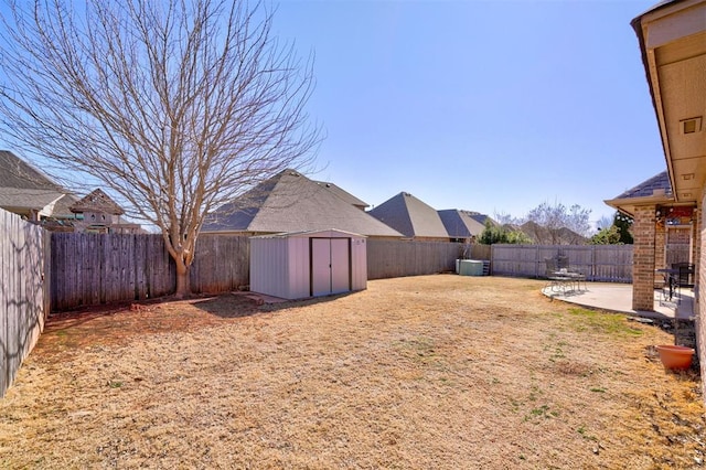 view of yard featuring an outbuilding, a fenced backyard, a patio, and a storage unit