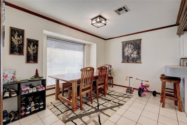 dining space with light tile patterned floors, baseboards, visible vents, and crown molding