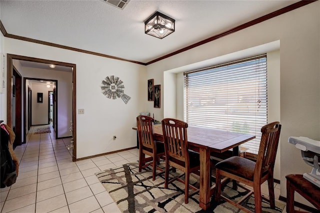 dining area featuring light tile patterned floors, ornamental molding, visible vents, and baseboards