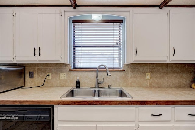 kitchen featuring black dishwasher, a sink, and white cabinets