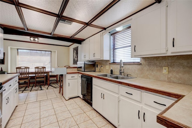 kitchen with black dishwasher, white cabinetry, tasteful backsplash, and a sink