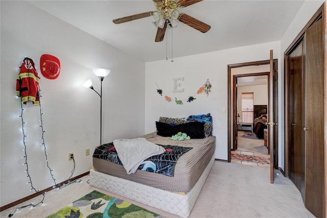 bedroom with a ceiling fan, a closet, and light colored carpet