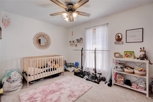 bedroom featuring carpet floors, a crib, and a ceiling fan