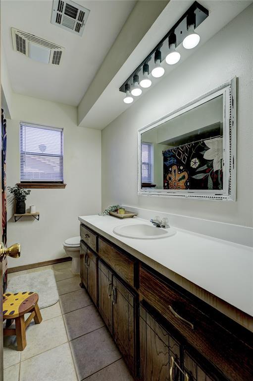 bathroom with toilet, tile patterned flooring, visible vents, and vanity