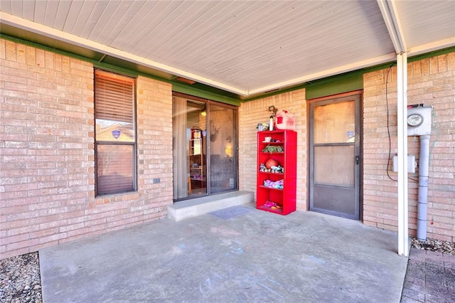 property entrance with a porch and brick siding