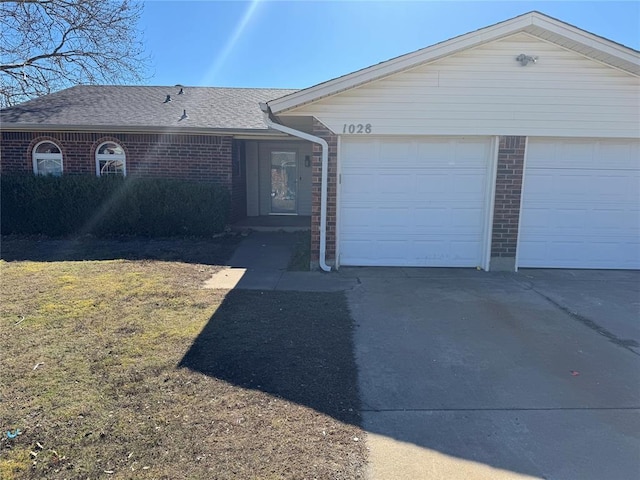 single story home with brick siding, concrete driveway, an attached garage, and a shingled roof