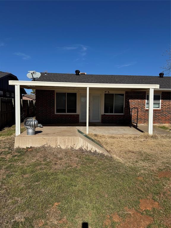 rear view of property with brick siding, a patio area, a lawn, and fence