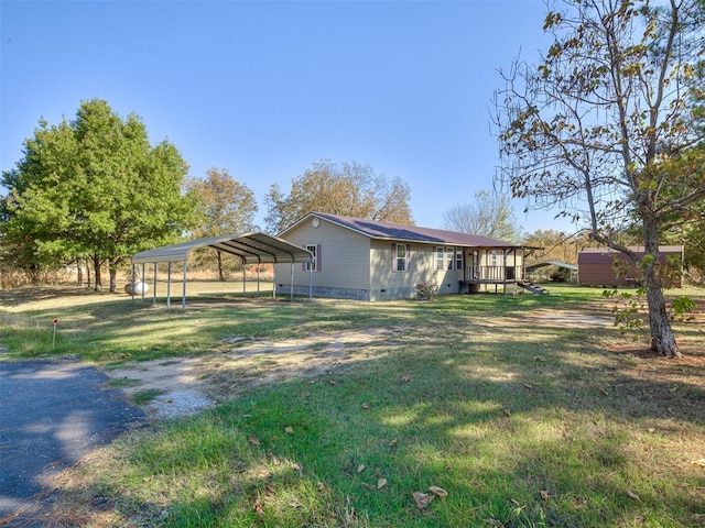 view of side of property featuring crawl space, a yard, driveway, and a detached carport