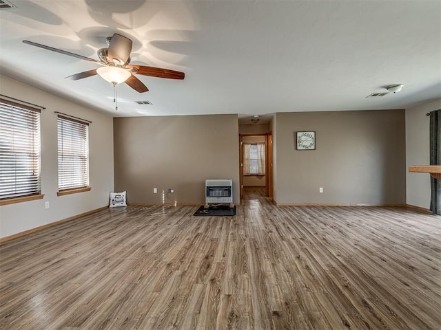 unfurnished living room featuring baseboards, wood finished floors, visible vents, and heating unit