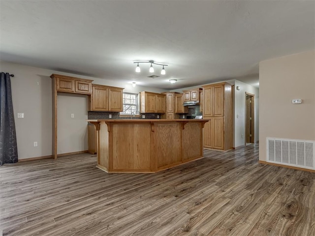 kitchen with light wood-style flooring, a kitchen bar, visible vents, and baseboards