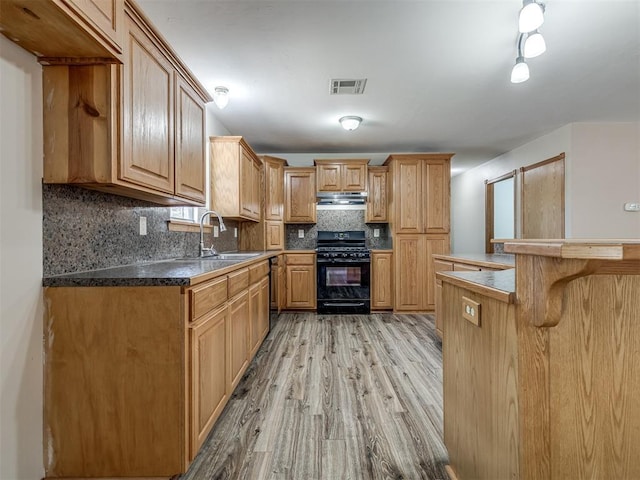 kitchen with visible vents, a kitchen breakfast bar, black range with gas stovetop, under cabinet range hood, and a sink