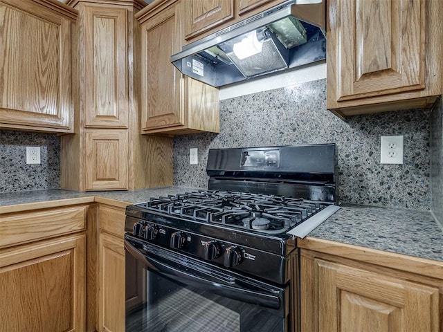 kitchen with black gas range oven, under cabinet range hood, tasteful backsplash, and light countertops