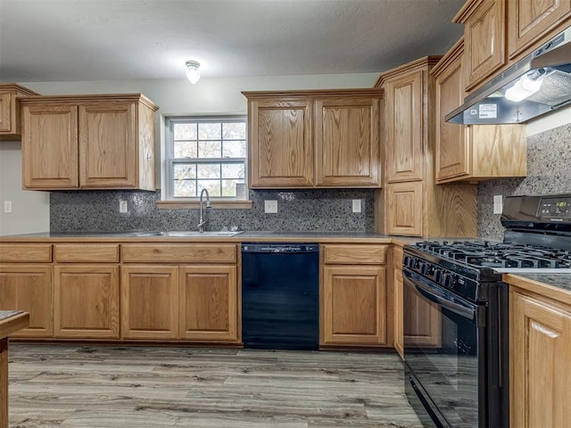 kitchen featuring black appliances, a sink, light wood-style flooring, and under cabinet range hood