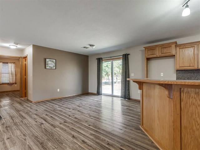 kitchen with a kitchen bar, light countertops, light wood-style flooring, decorative backsplash, and baseboards