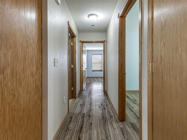 corridor featuring baseboards and wood finished floors