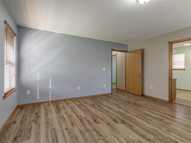 spare room featuring light wood-style floors and baseboards