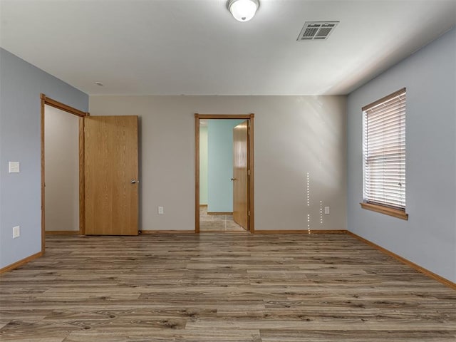 unfurnished bedroom featuring wood finished floors, visible vents, and baseboards