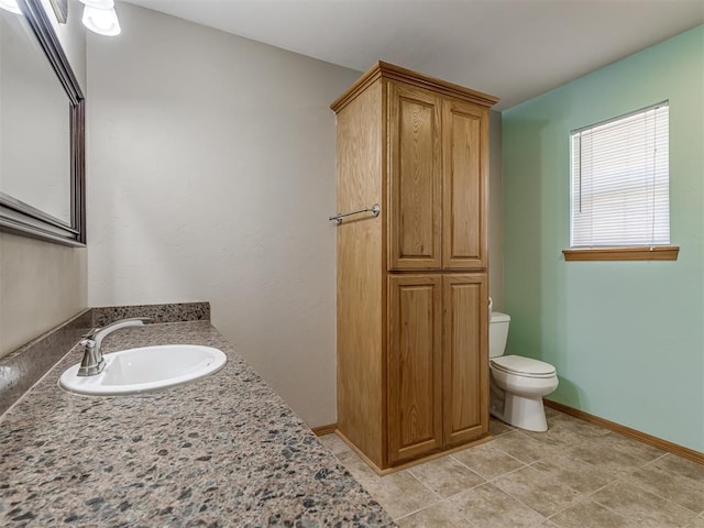 bathroom featuring vanity, tile patterned flooring, toilet, and baseboards