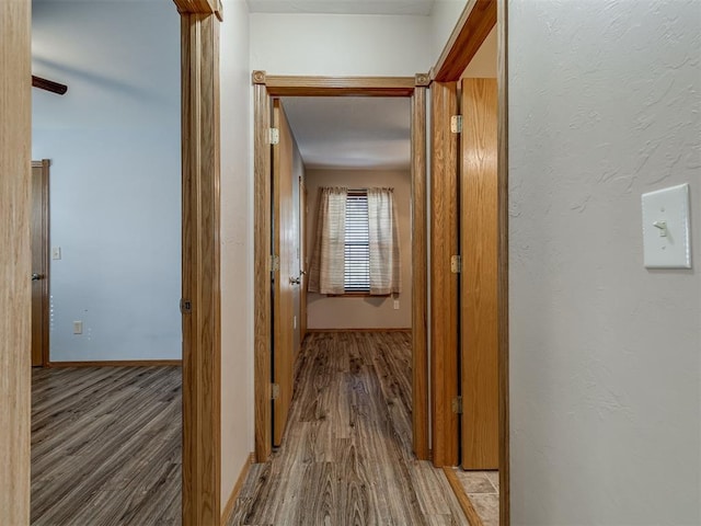 corridor featuring wood finished floors and baseboards