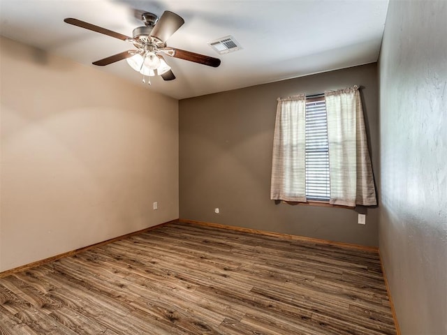 spare room with baseboards, wood finished floors, visible vents, and a ceiling fan