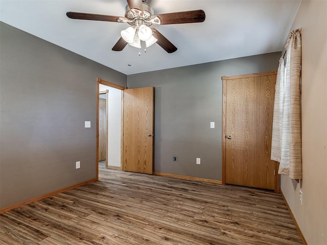 unfurnished bedroom with ceiling fan, baseboards, and wood finished floors