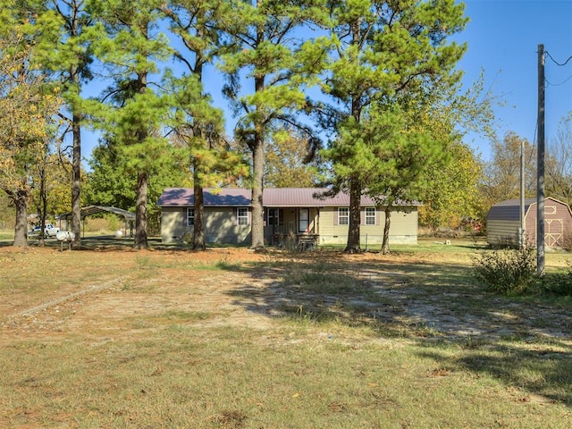 view of front of home with an outbuilding, metal roof, crawl space, a storage unit, and a front lawn