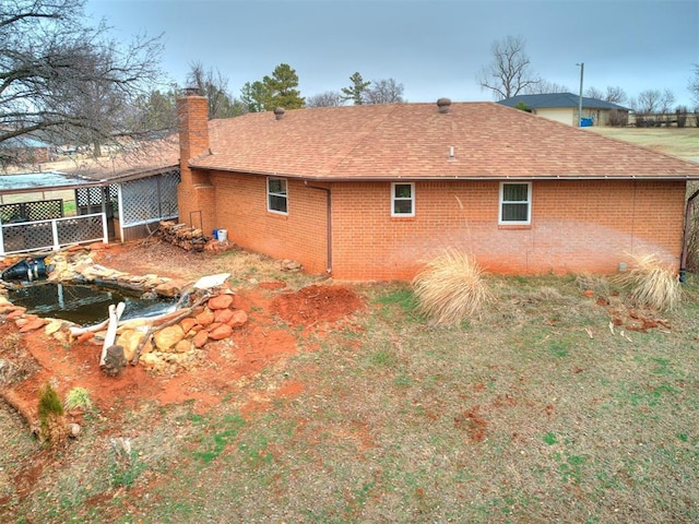 view of side of home featuring brick siding, roof with shingles, and a chimney