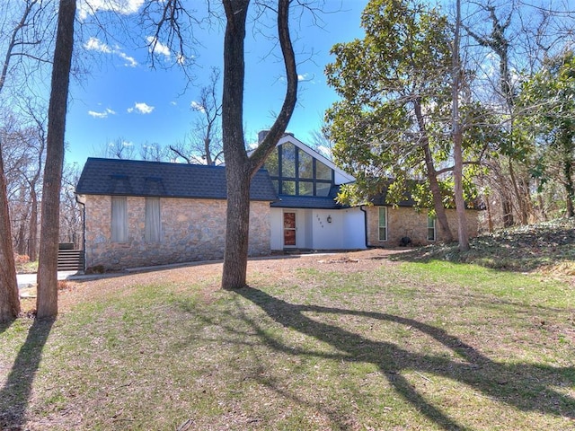 view of front of property featuring stone siding, roof with shingles, and a front lawn