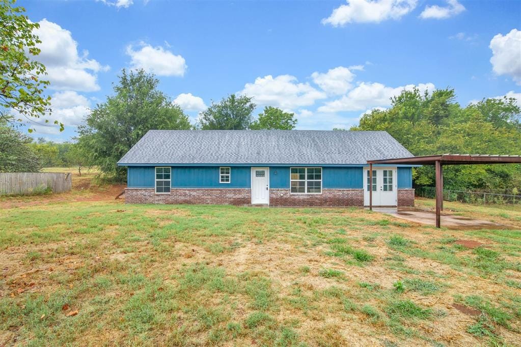 2704 County St Unit 2780, Chickasha, OK 73018 - back of house with brick siding, a lawn, fence, and an attached carport
