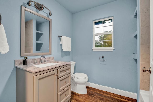 bathroom with toilet, baseboards, wood finished floors, and vanity