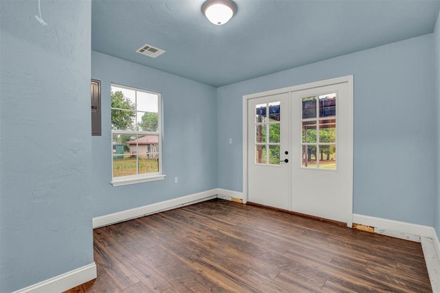 spare room featuring visible vents, baseboards, dark wood-style flooring, and french doors