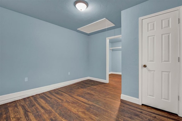 unfurnished bedroom featuring a closet, wood finished floors, attic access, and baseboards