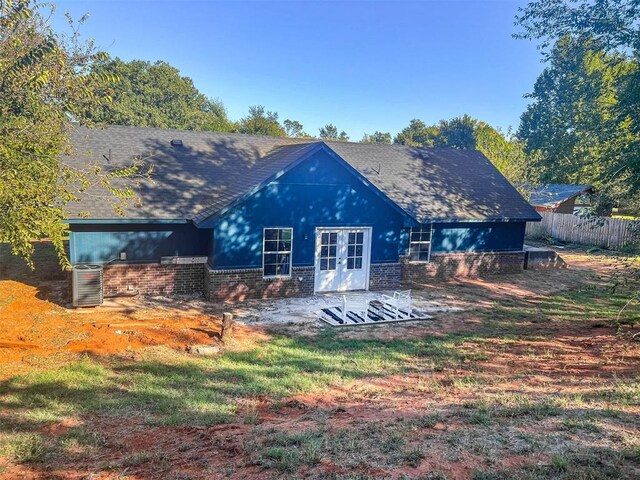 back of property with roof with shingles, fence, french doors, and brick siding