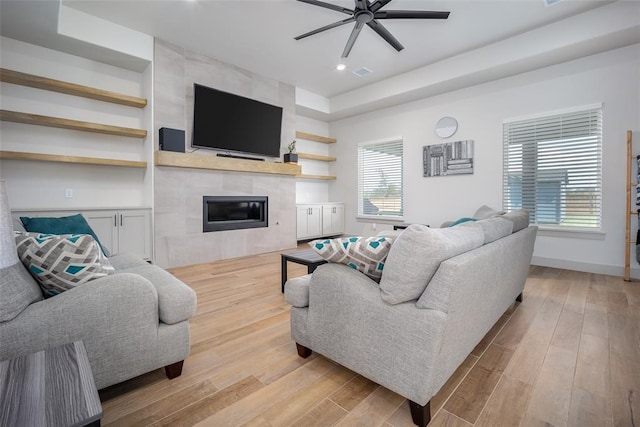 living room with visible vents, a fireplace, baseboards, and wood finished floors