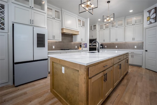 kitchen featuring stainless steel microwave, refrigerator with glass door, wood finished floors, and an inviting chandelier