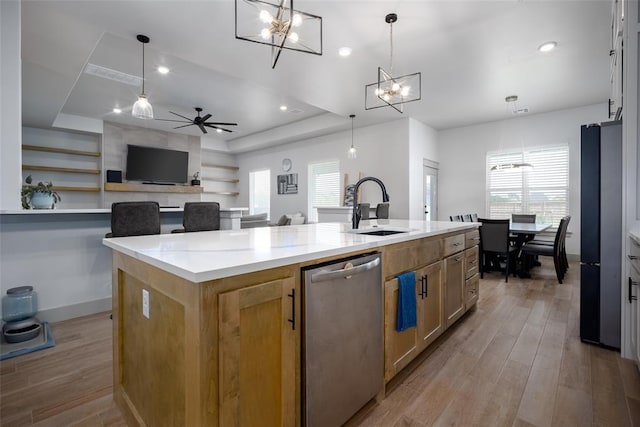 kitchen with a center island with sink, a sink, light wood-style flooring, and stainless steel dishwasher